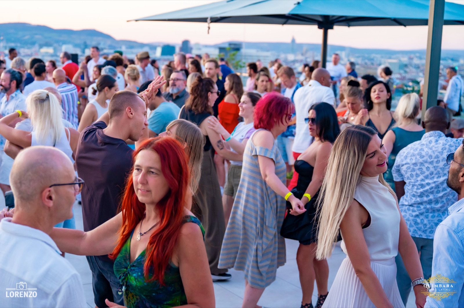 Menschen tanzen auf der Dachterrasse unter Sonnenschirmen